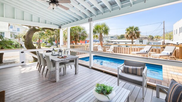 Une terrasse extérieure couverte avec une piscine, des chaises longues et une table à manger.