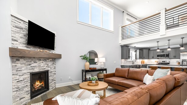A modern living room with a fireplace, leather sofa, and a flat-screen TV mounted above it. - Lux canalfront home. Firepit, kayaks,paddleboat, 20 foot dock, chefs kitchen! (Houghton Lake)