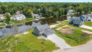 A residential area with houses, a lake, and a dock. - Lux canalfront home. Firepit, kayaks,paddleboat, 20 foot dock, chefs kitchen! (Houghton Lake)