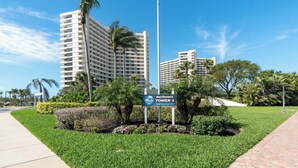 Een bord voor Northwest Tower 3, een hoog hotel met een modern design, omringd door verzorgde beplanting en palmbomen.