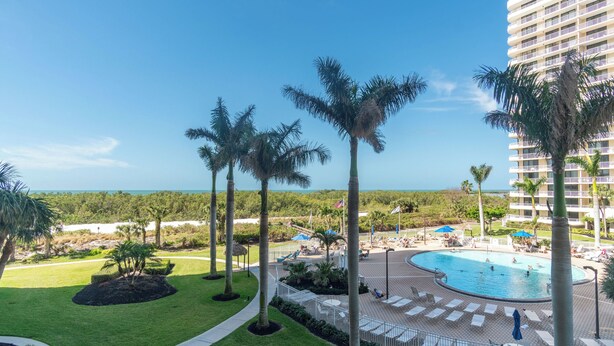 Een resort met een zwembad, palmbomen en uitzicht op de oceaan.