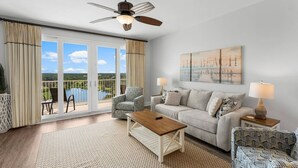 A spacious living room with a large window offering a scenic view, a ceiling fan, and a cozy seating area. - The Beach is Calling at this 13th Floor Beauty (Panama City Beach)