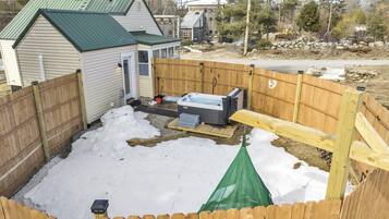 A backyard with a hot tub, wooden fence, and a small shed.