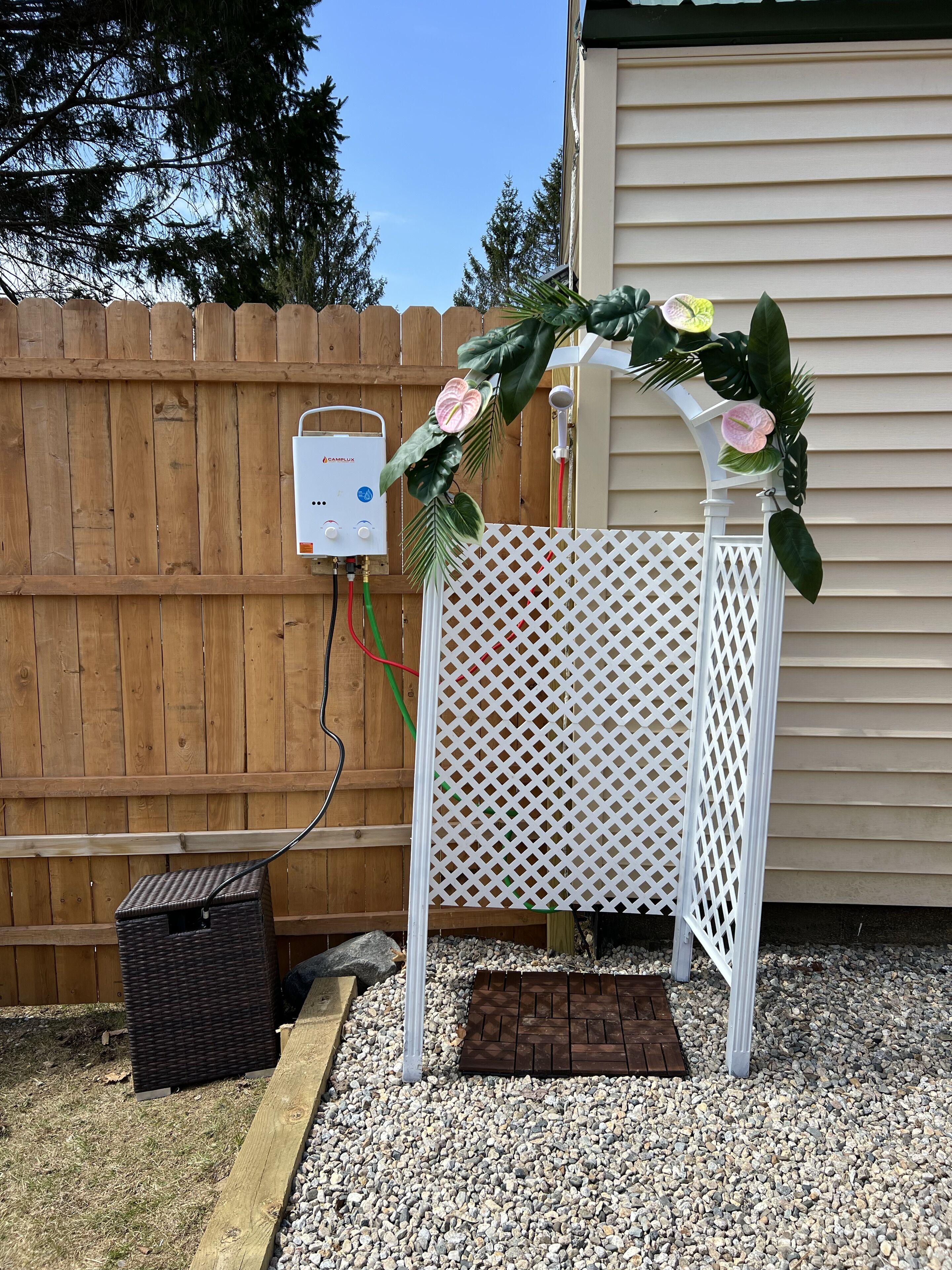 Un arco de celosía blanca con un elemento acuático y un calentador de agua Camplux.