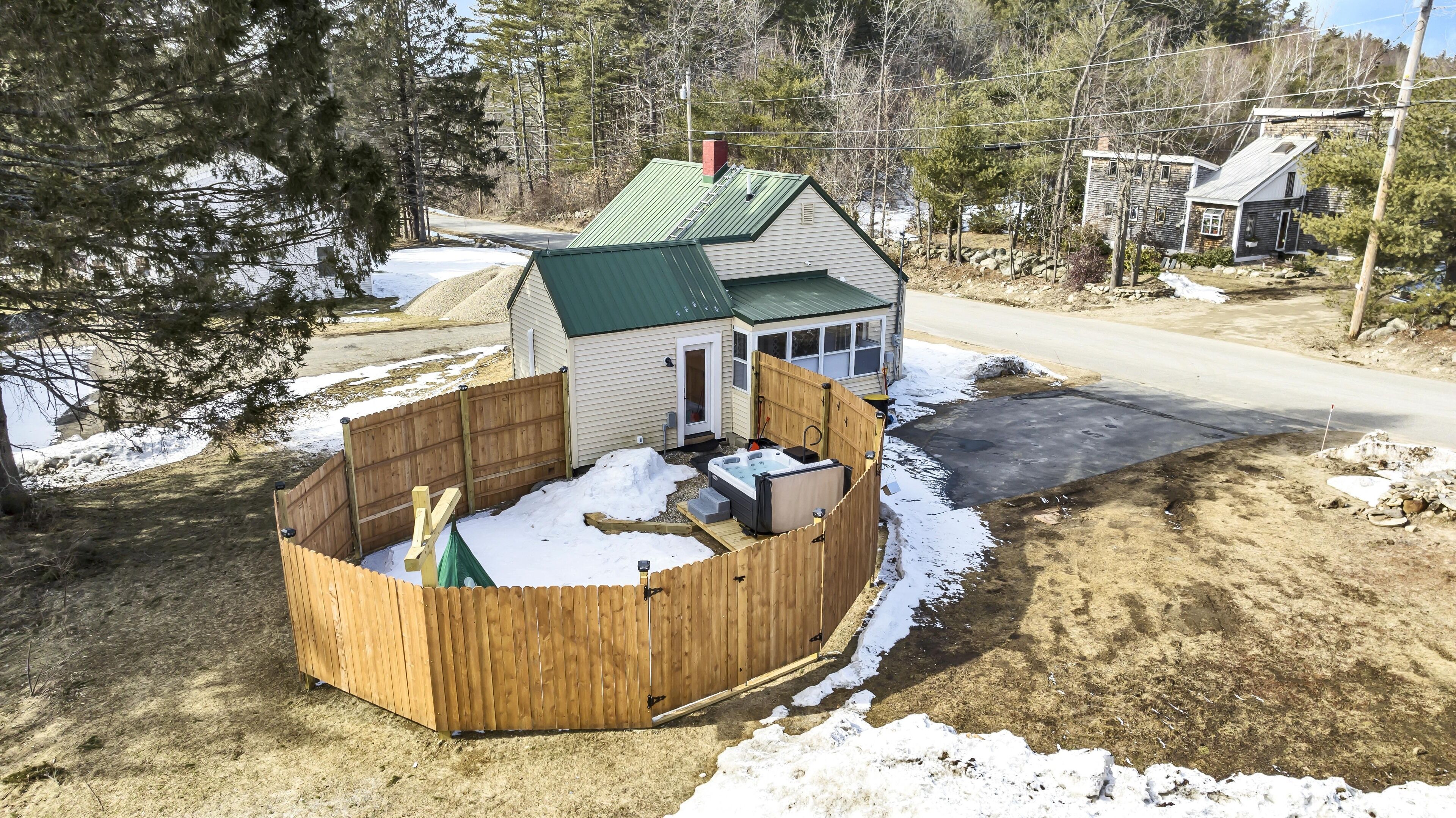 A house with a green roof, a wooden deck, and a hot tub.