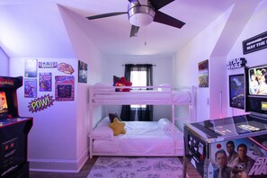 Een slaapkamer met stapelbedden, een plafondventilator, posters, een Star Wars poster en een gameconsole.