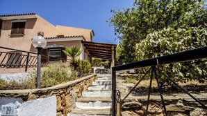 A stone staircase leading to a building with a number 19 sign, surrounded by greenery and a metal railing. - Casa Vacanza La Collinetta | 2 bedroom, 2 baths, veranda (budoni)