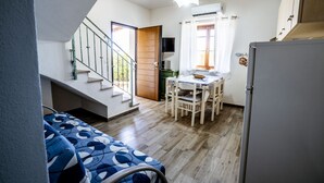 A compact living space with a dining area, a kitchen, and a staircase leading to an upper level. - Casa Vacanza La Collinetta | 2 bedroom, 2 baths, veranda (budoni)