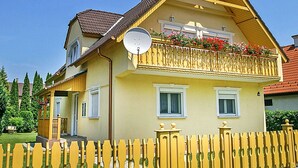 Ein zweistöckiges Haus mit Balkon, Satellitenschüssel und einem weißen Zaun.