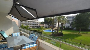 Un balcón con mesa y sillas, una piscina y vistas a una zona residencial.