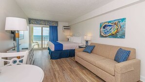 Ein Hotelzimmer mit einem Bett, einem Sofa, einem Esstisch und einem Bild an der Wand.