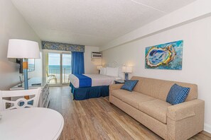 Une chambre d’hôtel avec un lit, un canapé, une table à manger et un tableau au mur.