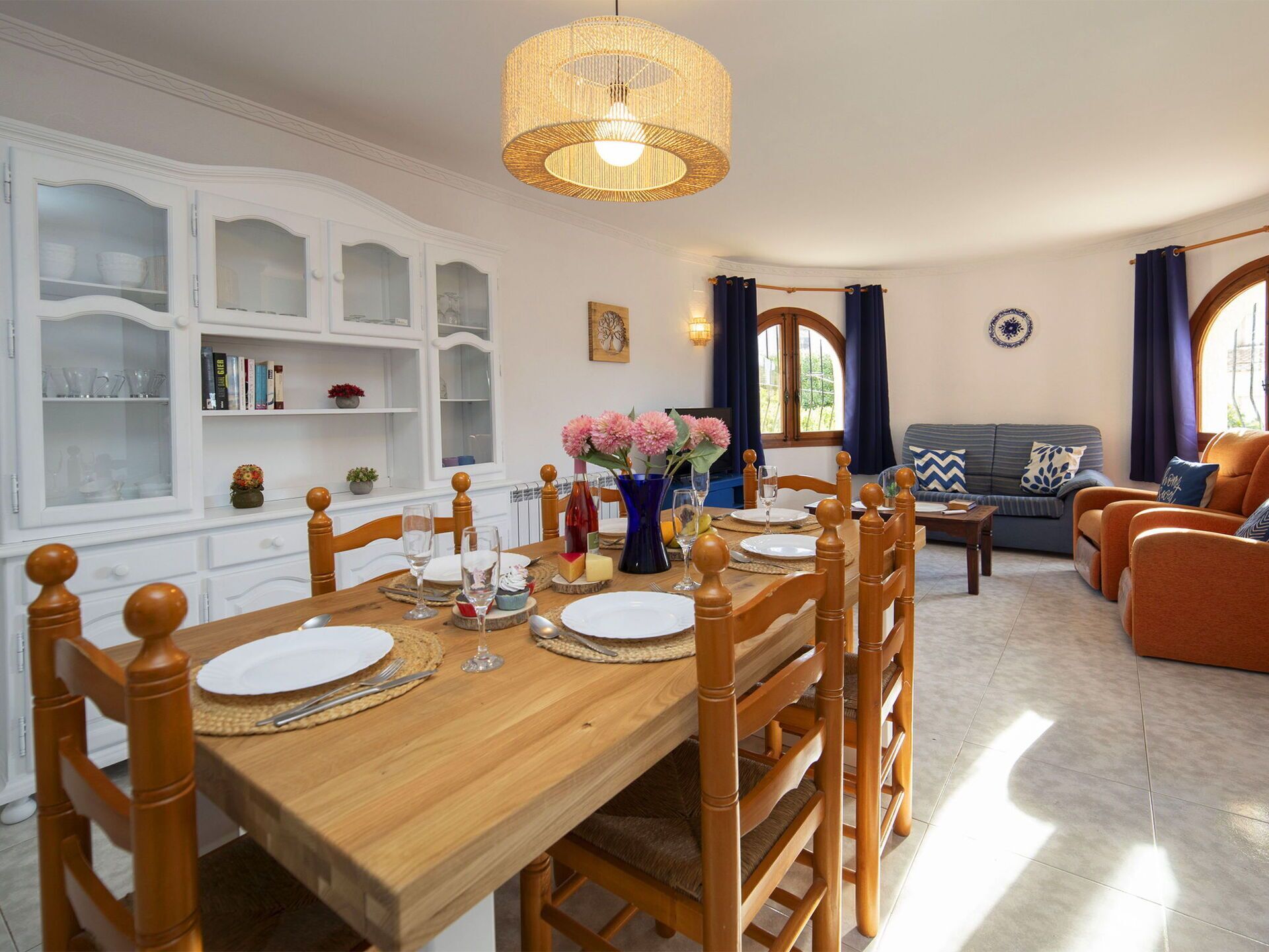 A dining area with a wooden table set for four, surrounded by wooden chairs.