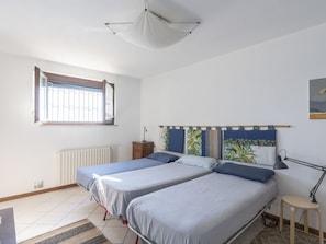 A bedroom with two beds, a radiator, a window with bars, a small table, and a hanging light fixture. - Beautiful  villa for 9 people with WIFI, terrace and pets allowed (Andora)