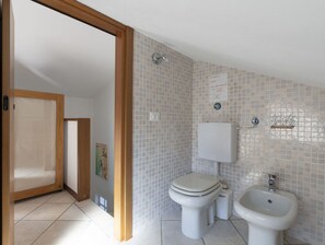 A bathroom with a toilet, bidet, and sink, tiled walls, and a wooden door frame. - Beautiful  villa for 9 people with WIFI, terrace and pets allowed (Andora)