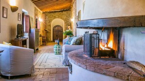 Una sala de estar acogedora con chimenea, paredes de piedra y vigas de madera.