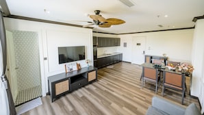 A modern kitchen with dark cabinets, a large island, and a dining area with a table and chairs.