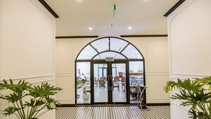 A hotel entrance with a checkered floor, potted plants, and a sign reading "NHA HANG RESTAURANT".