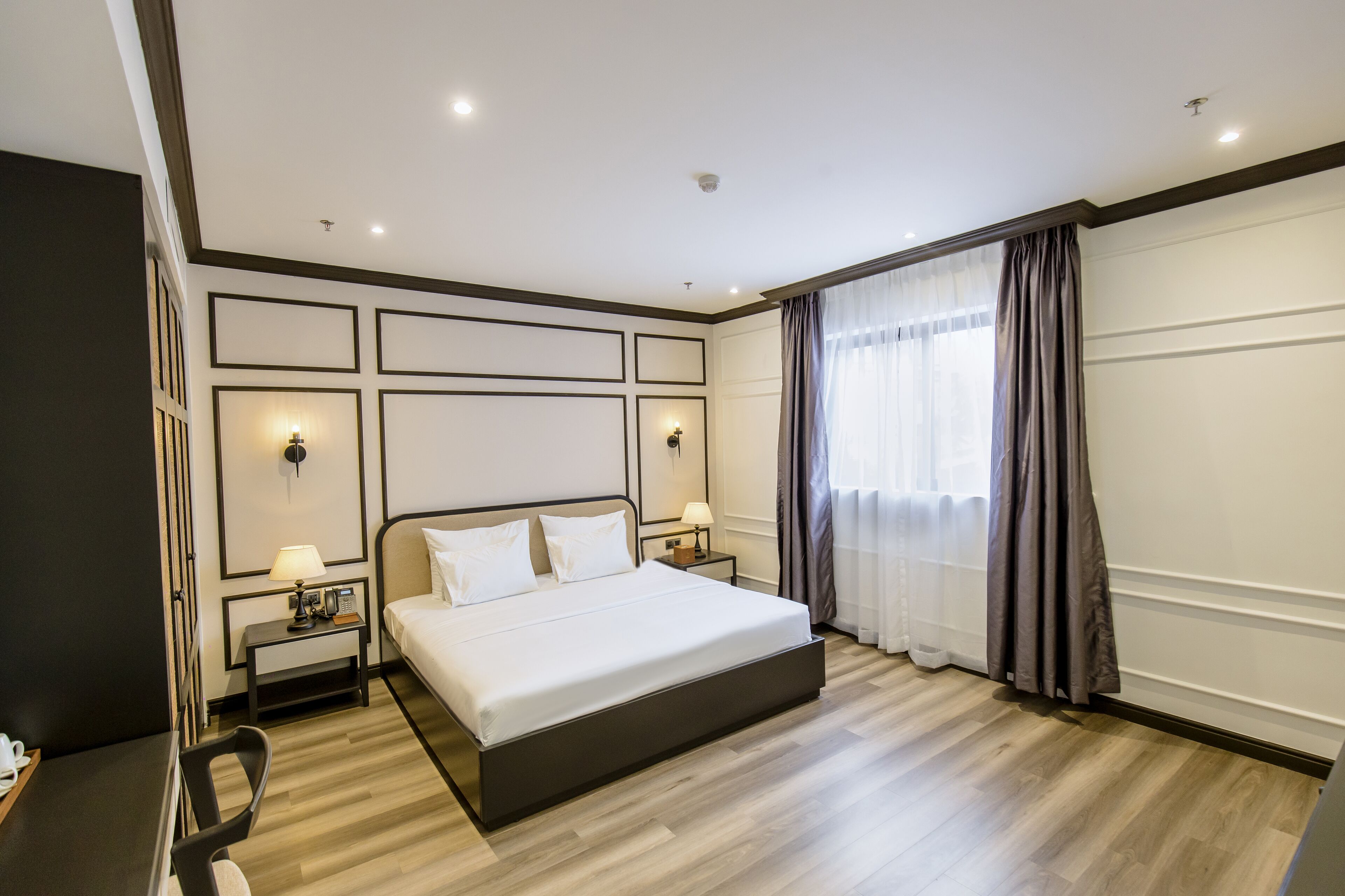 Une chambre d’hôtel moderne avec un grand lit, des tables de chevet avec des lampes, un bureau et une chaise.