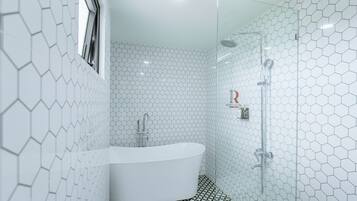 A modern bathroom with a hexagonal tile pattern, a freestanding bathtub, and a glass-enclosed shower area.