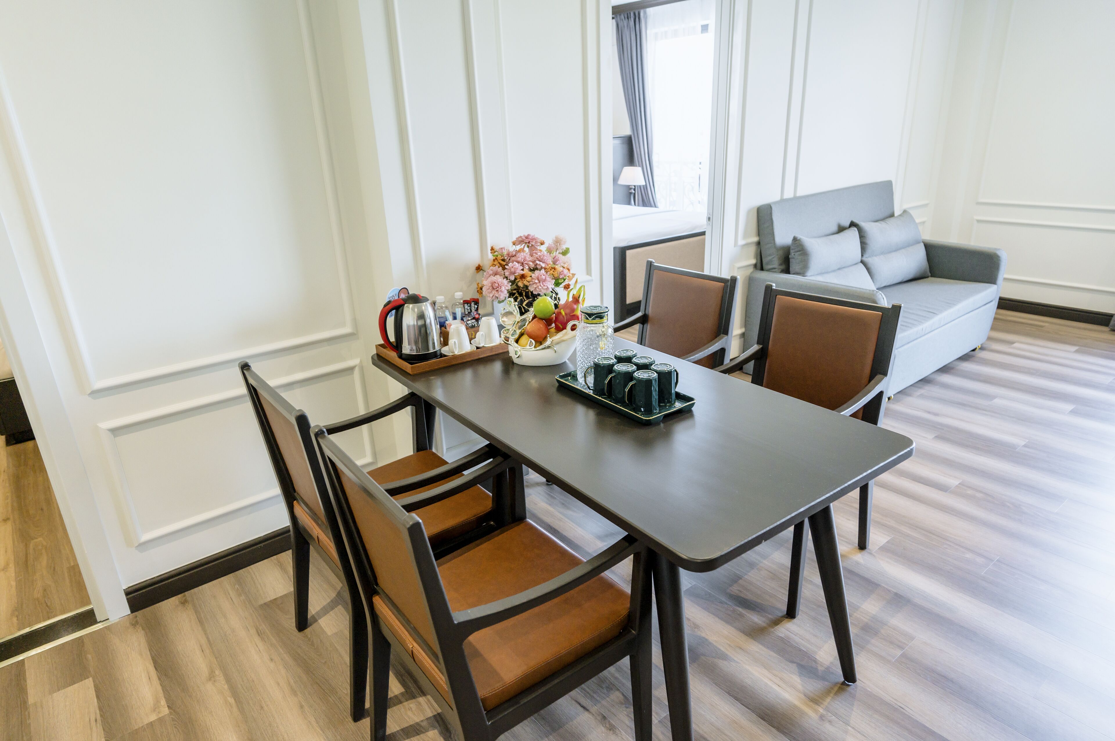 Un coin repas avec une table dressée pour quatre personnes, un canapé et une fenêtre avec des rideaux.