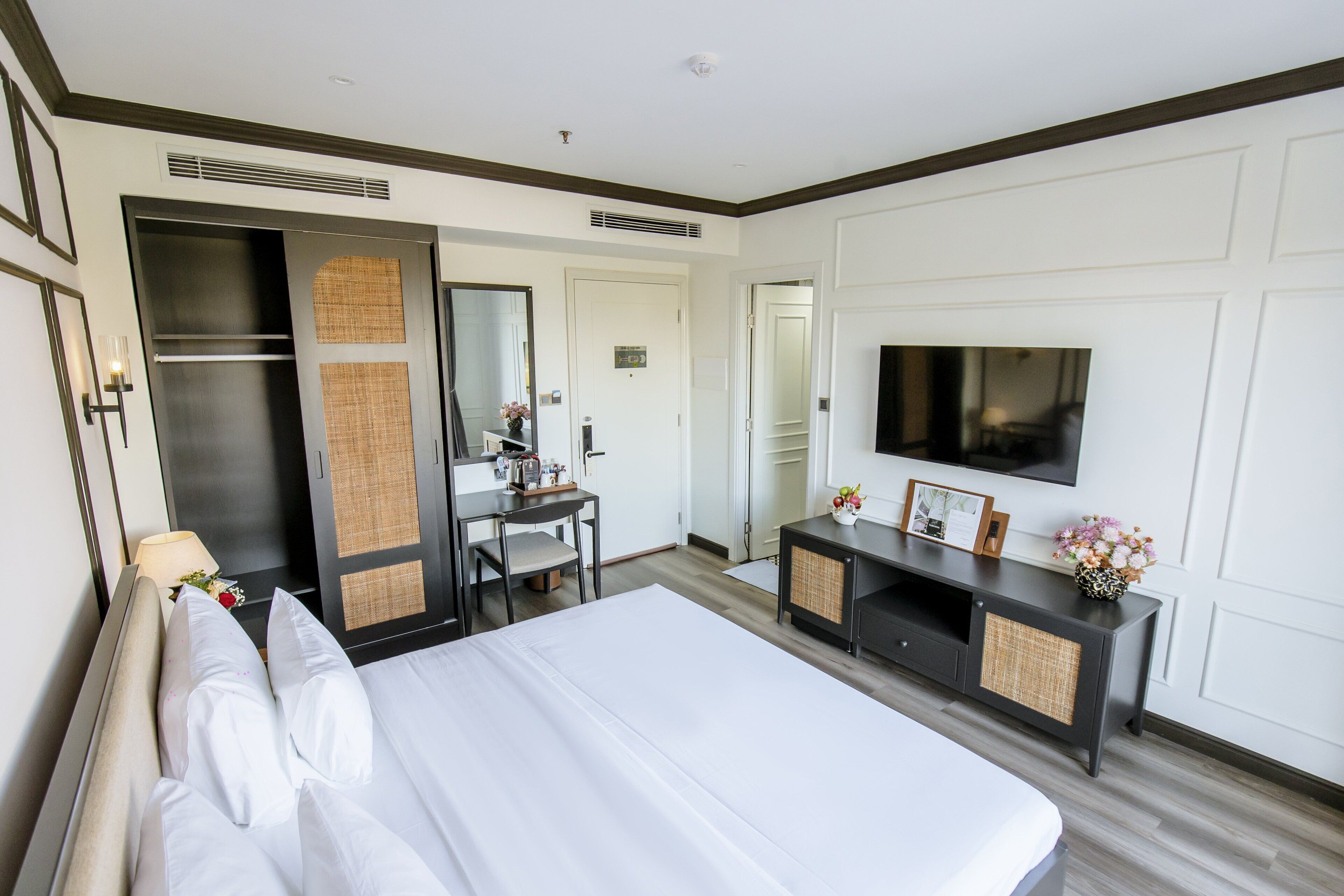 Una habitación de hotel con una cama grande, un escritorio, un televisor y un armario.