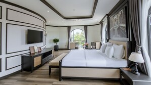 A modern bedroom with a large bed, a TV, and a balcony view.