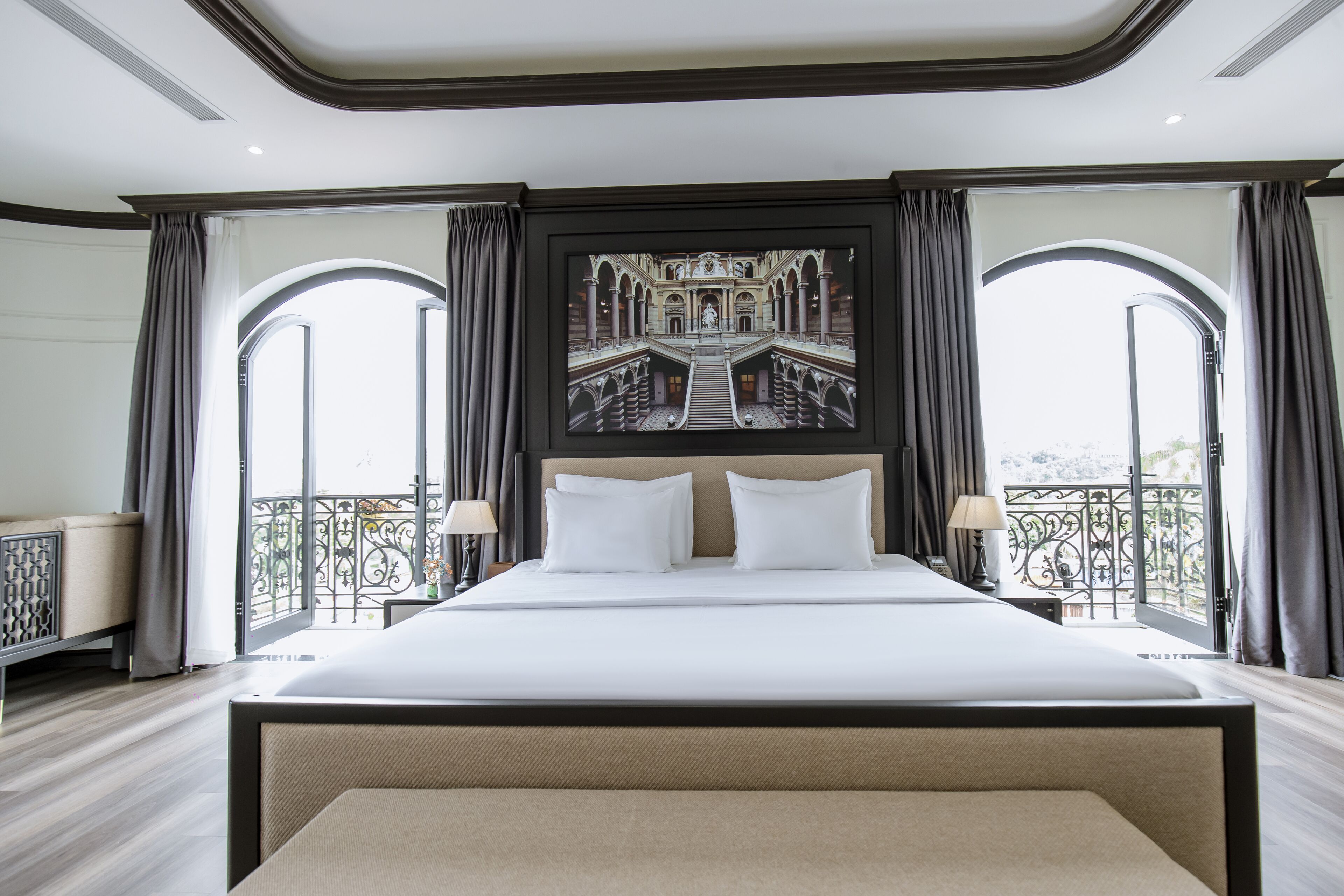 A large bed with a headboard, two bedside tables with lamps, and a large framed picture above the bed.