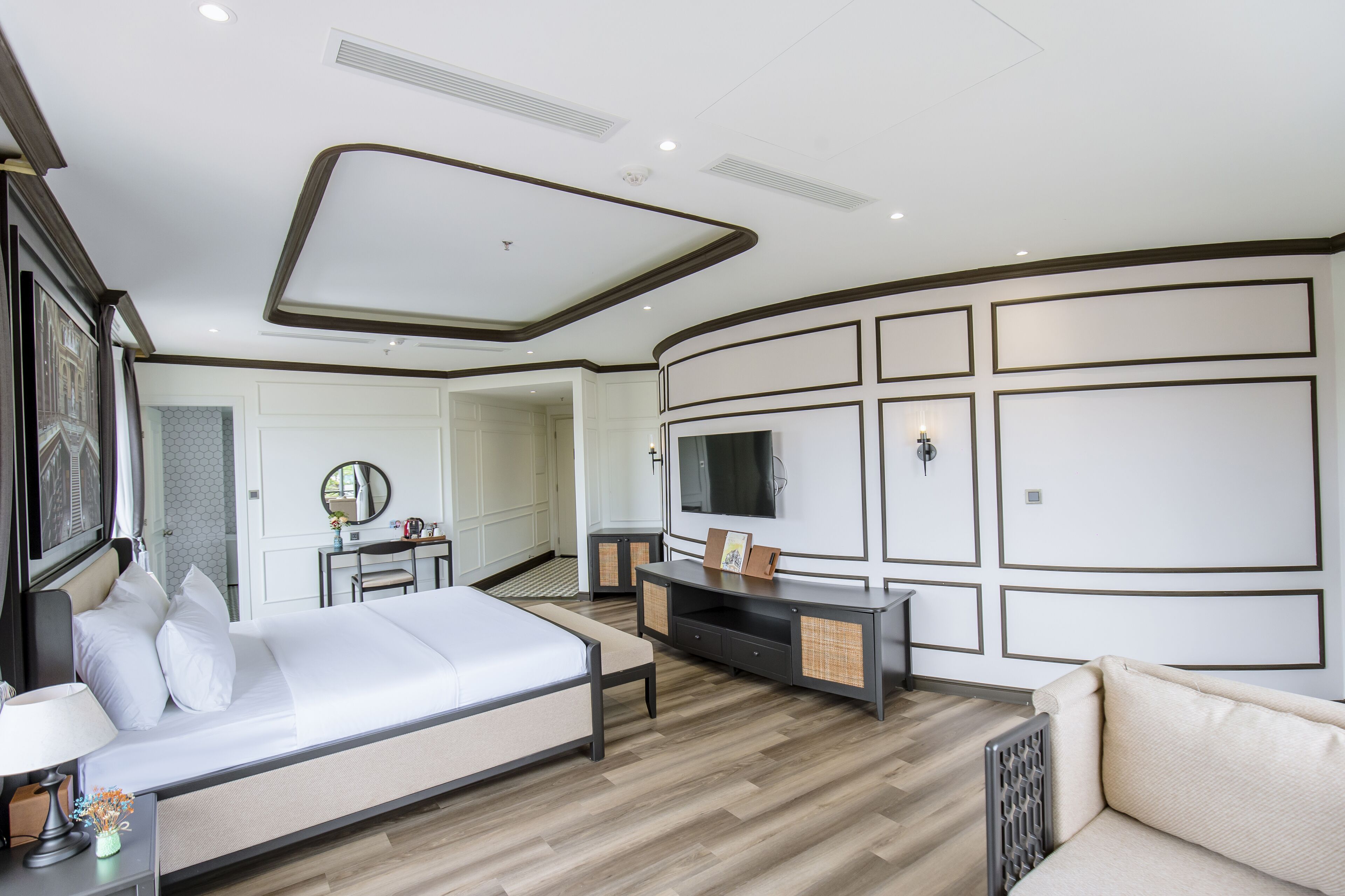 A modern bedroom with a large bed, a TV mounted on the wall, and a desk with a chair.