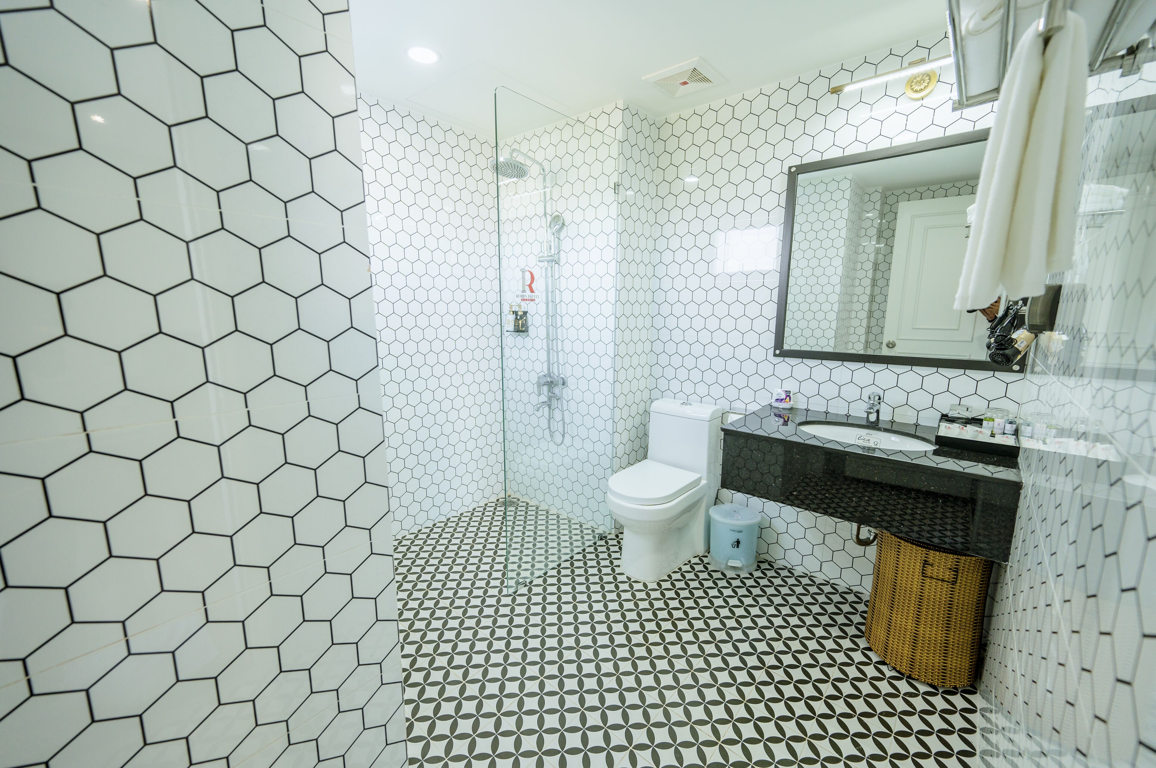 A bathroom with a hexagonal tile pattern, a white toilet, a sink, and a mirror.