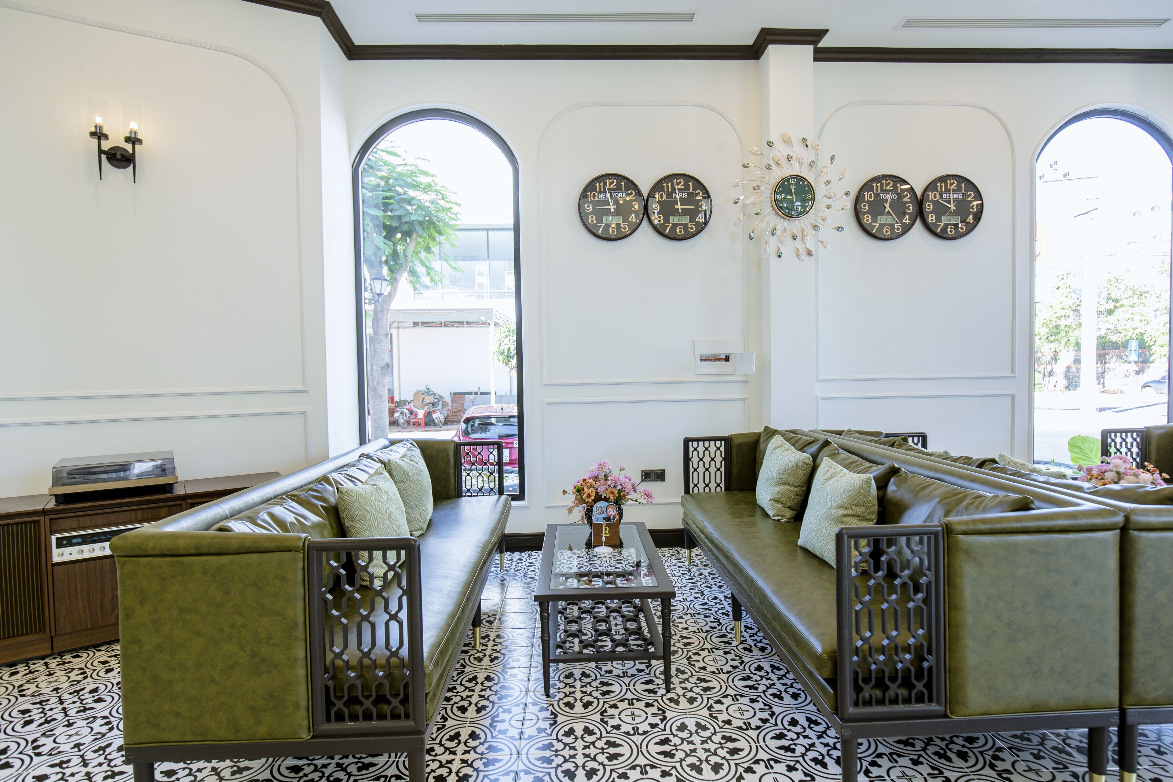 A modern living room with a sectional sofa, a coffee table, and decorative clocks on the wall.