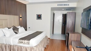 Une chambre d’hôtel moderne, dotée d’un grand lit, d’un bureau et d’un téléviseur fixé au mur.