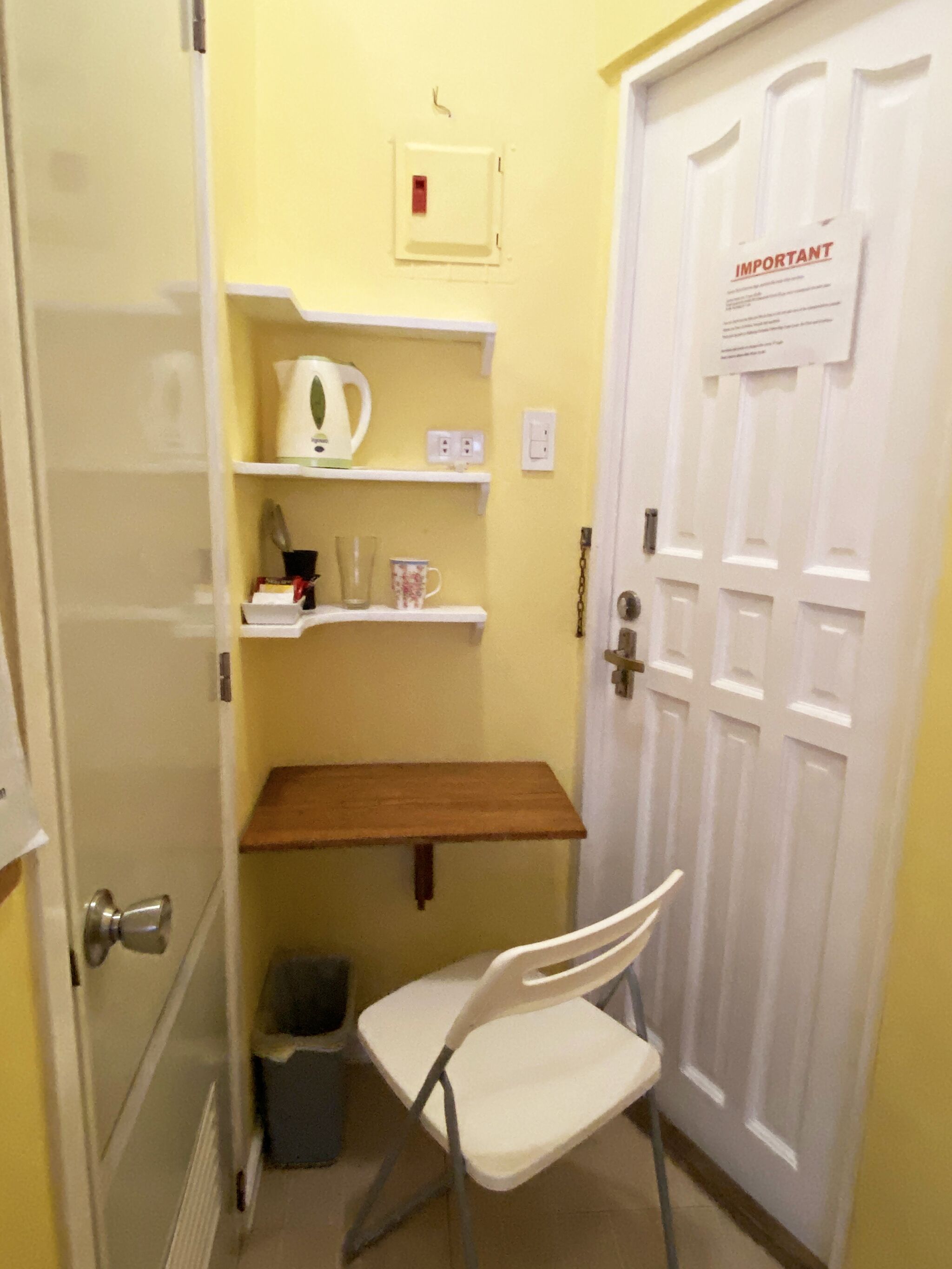 A small room with a white chair, a wooden shelf, and a white door with an 'IMPORTANT' sign.