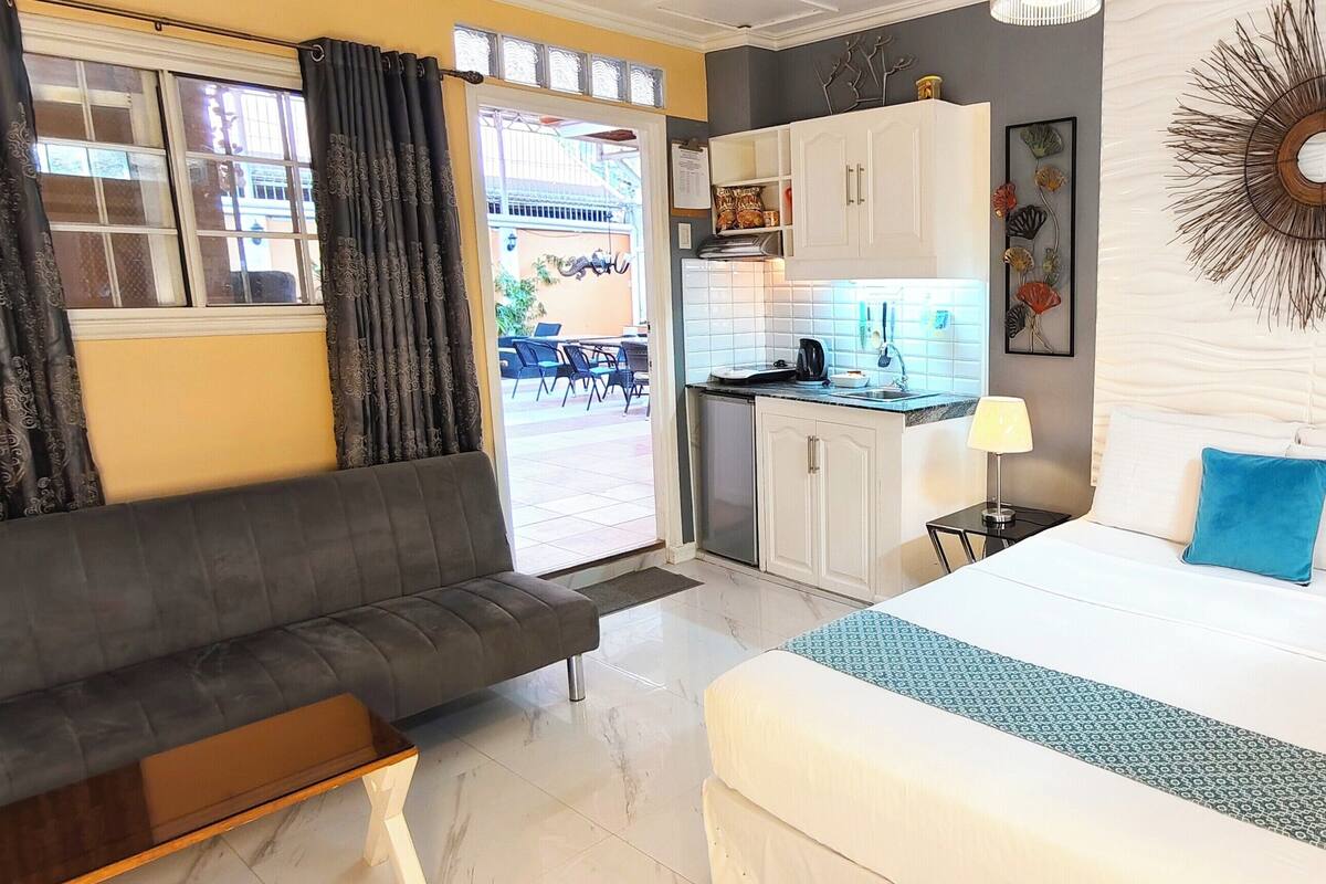 Une chambre d’hôtel avec un lit, un canapé, une kitchenette et une vue sur l’extérieur.