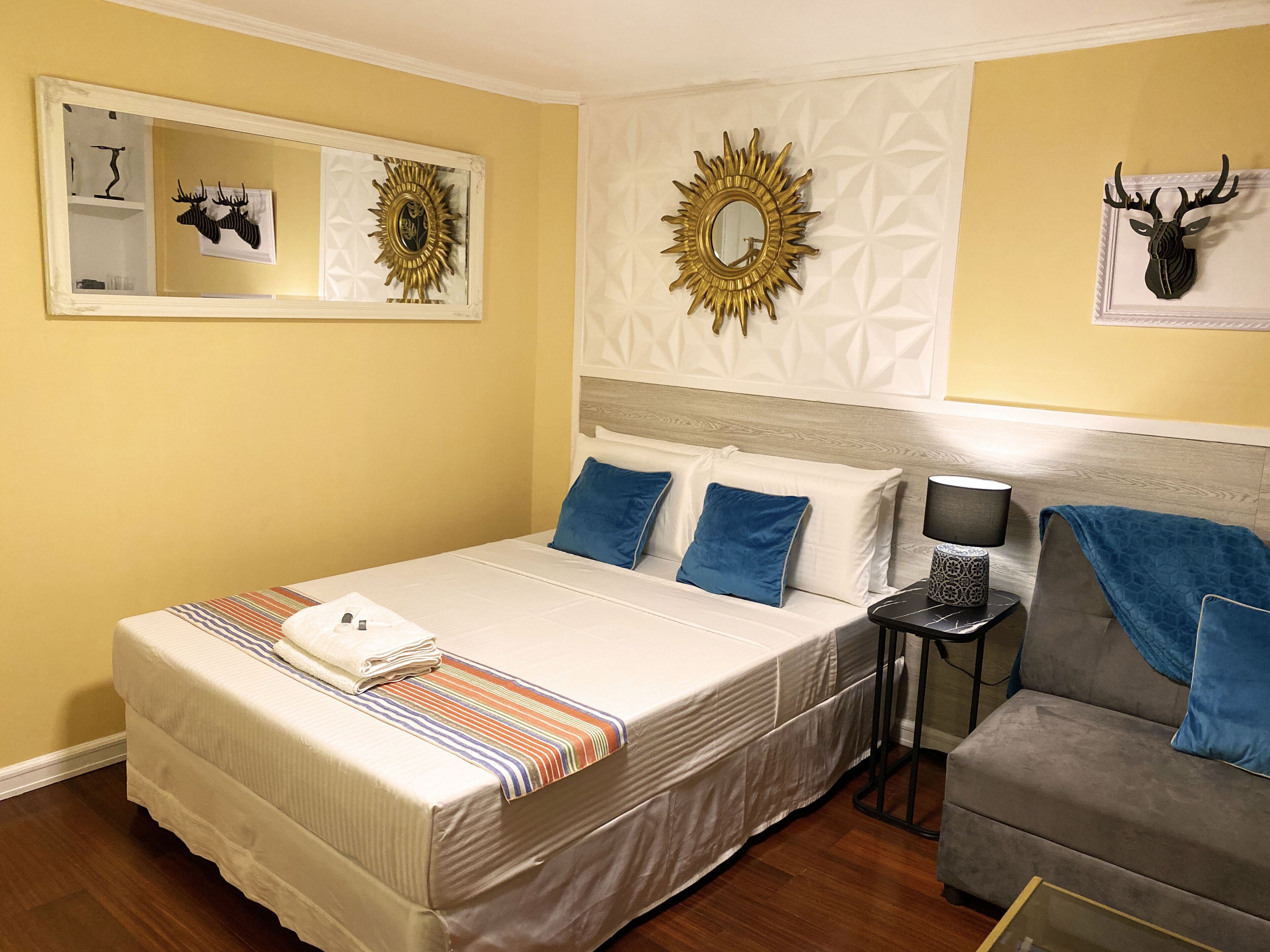 A hotel room with a large bed, a small sofa, a nightstand, and decorative wall art.