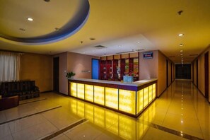 A hotel reception area with a reception desk, a seating area with a sofa, and a corridor leading to other rooms. - Yangfang Dadu Hotel (Beijing)