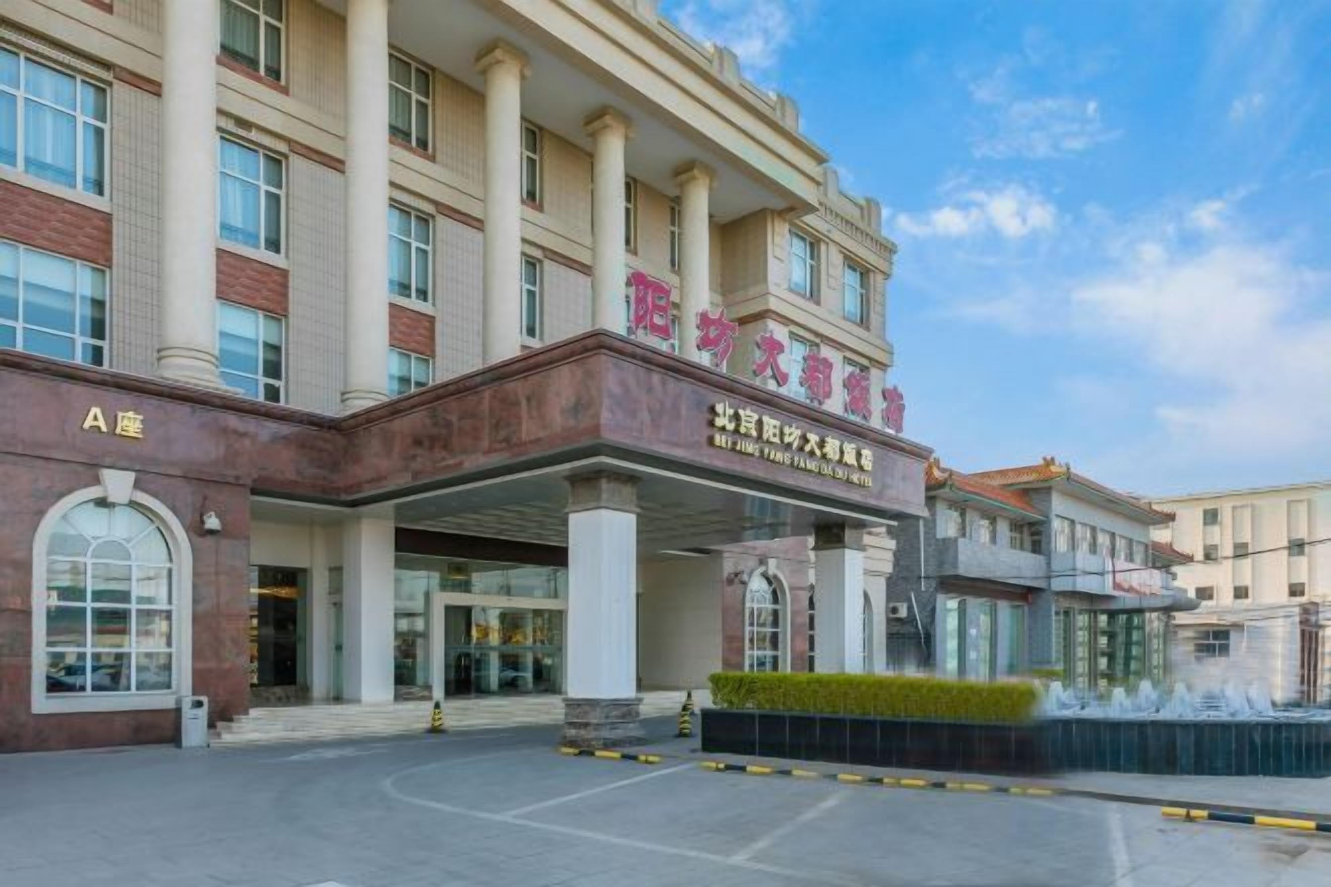 A hotel entrance with a covered area, large windows, and a clear sky.