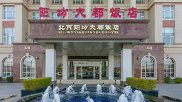 A hotel entrance with a fountain in front, featuring a sign with both Chinese and English text.