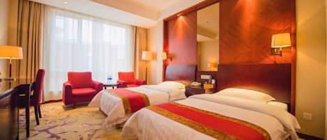 A hotel room with two beds, a desk, a chair, and a large mirror.
