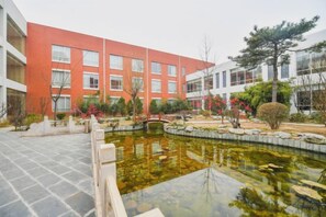 A courtyard with a pond, a red building, and a white building with multiple windows. - Yangfang Dadu Hotel (Beijing)