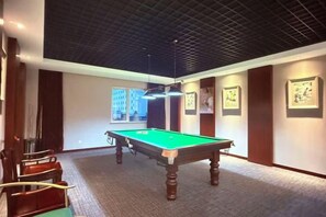 A pool table in a room with a high ceiling, framed pictures on the walls, and a carpeted floor. - Yangfang Dadu Hotel (Beijing)