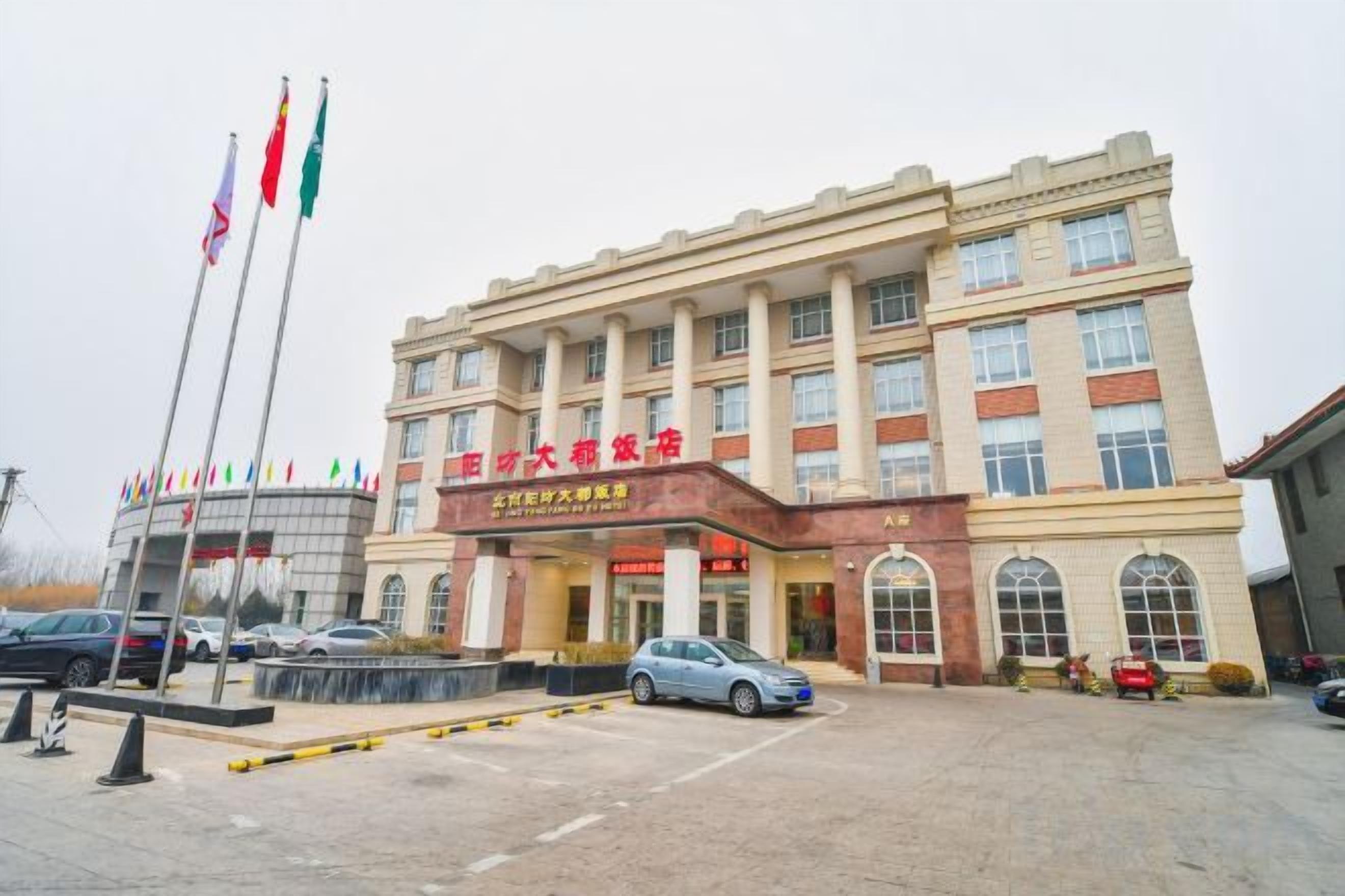 A hotel with a prominent entrance, multiple flags, and a parking lot.