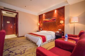 A hotel room with a bed, red chairs, a small table with a water bottle, and a painting on the wall. - Yangfang Dadu Hotel (Beijing)
