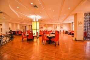 A spacious dining area with multiple tables and chairs, a central pillar, and a decorative wall. - Yangfang Dadu Hotel (Beijing)