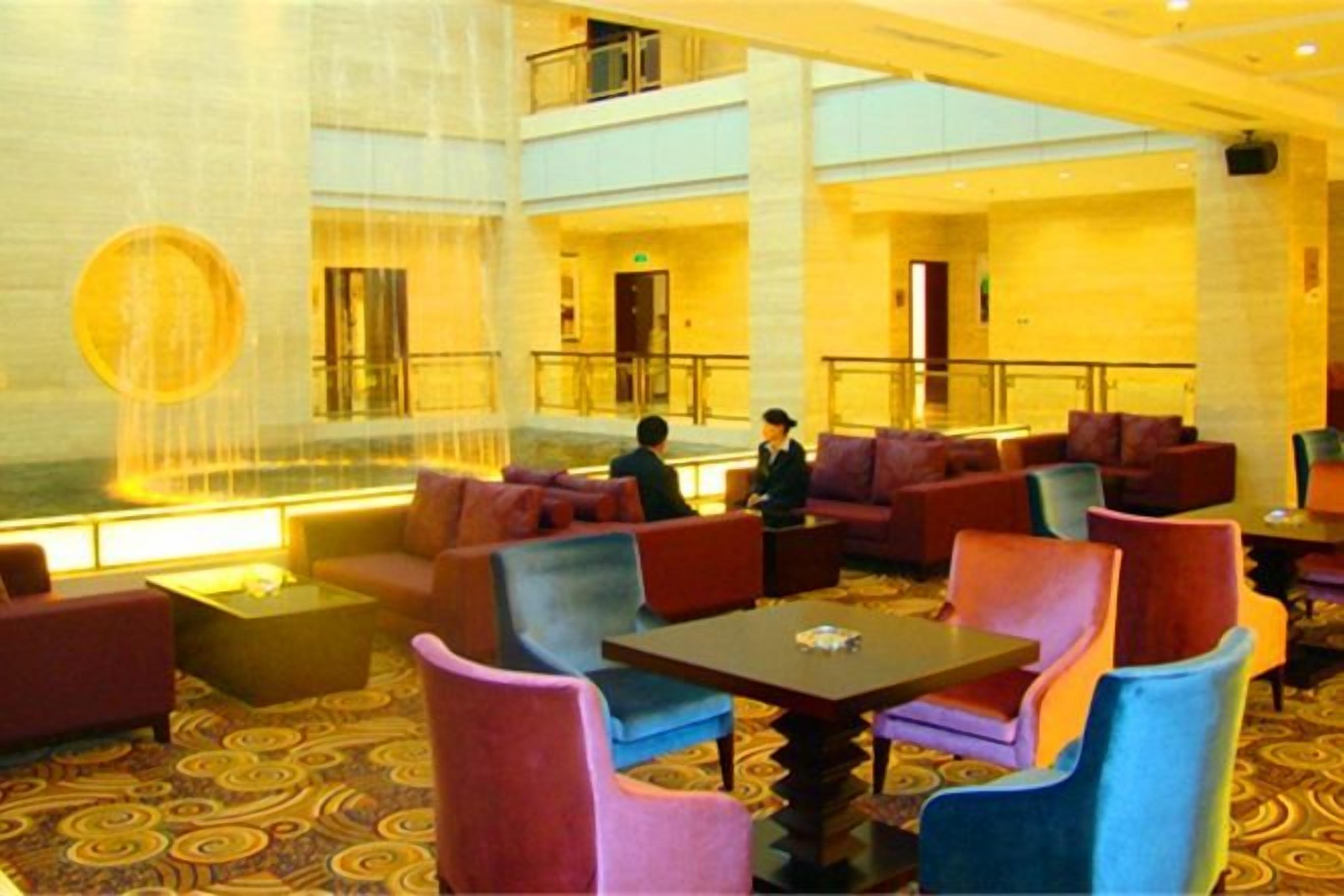 A hotel lobby with a central fountain, seating areas, and a high ceiling.