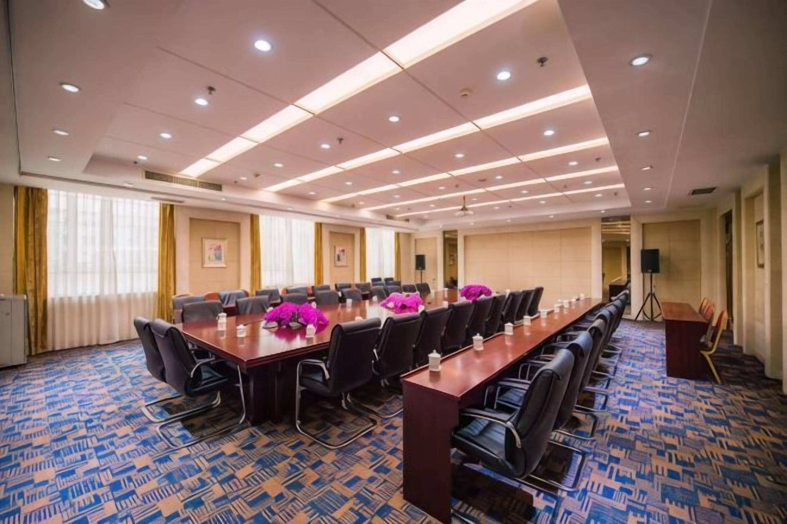 A conference room with a long table, multiple chairs, and a carpeted floor.