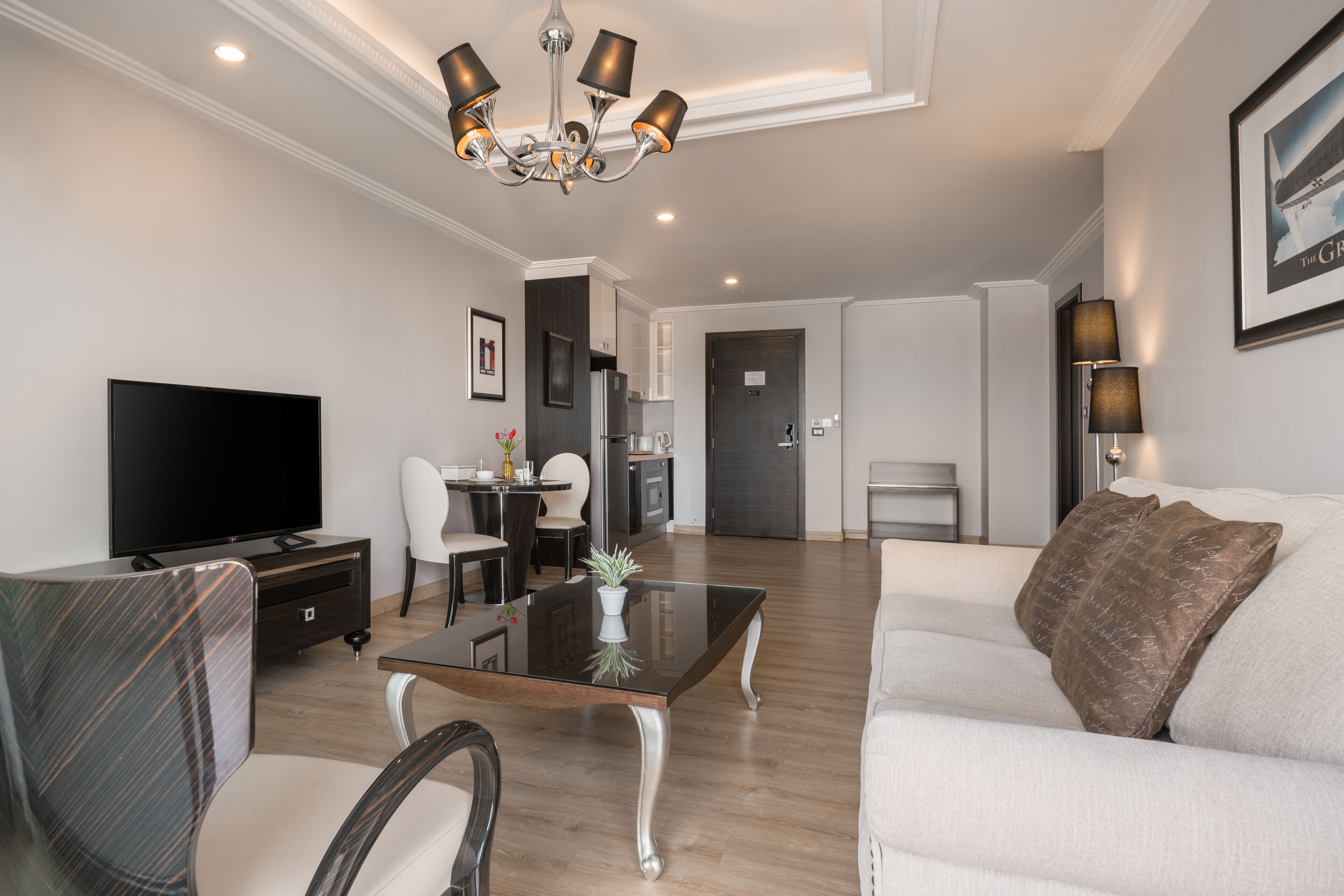 A modern living room with a flat-screen TV, a glass coffee table, and a sofa.