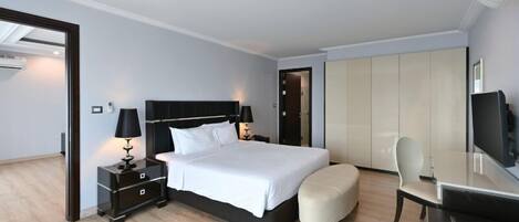 Una habitación de hotel moderna con una cama grande, un escritorio, una silla y un armario.