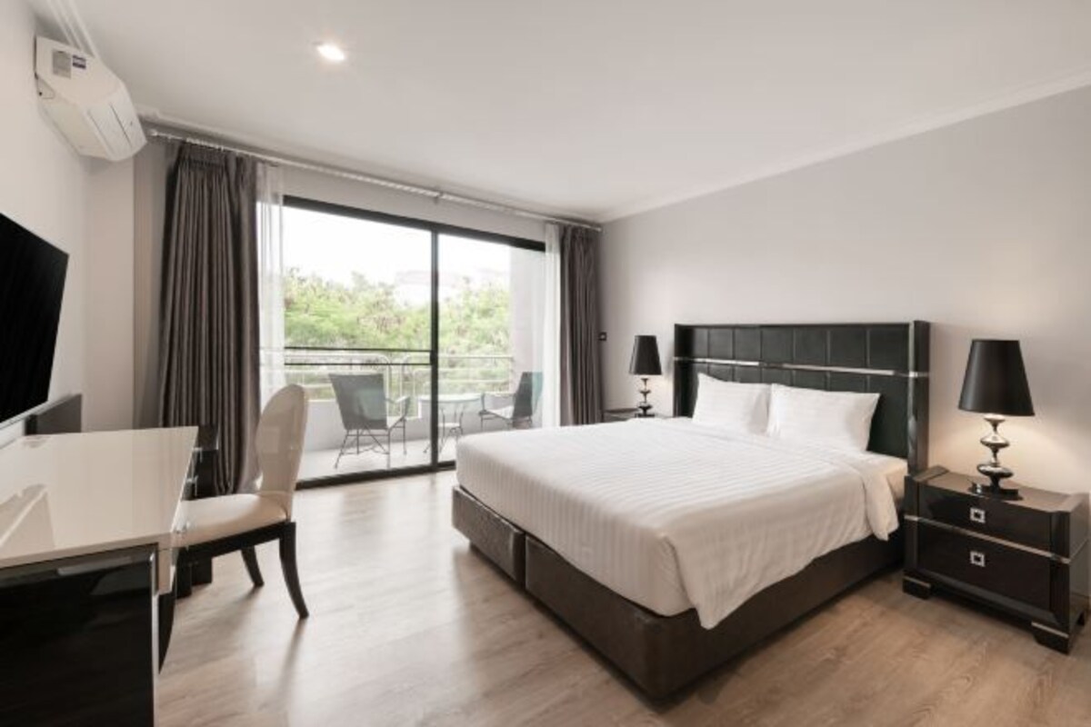 A modern hotel room with a large bed, a desk, and a chair.
