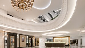 A spacious lobby with a grand chandelier, a reception desk, and a high ceiling with skylights. - Sirin Exclusive Hotel & Residence (Pattaya)